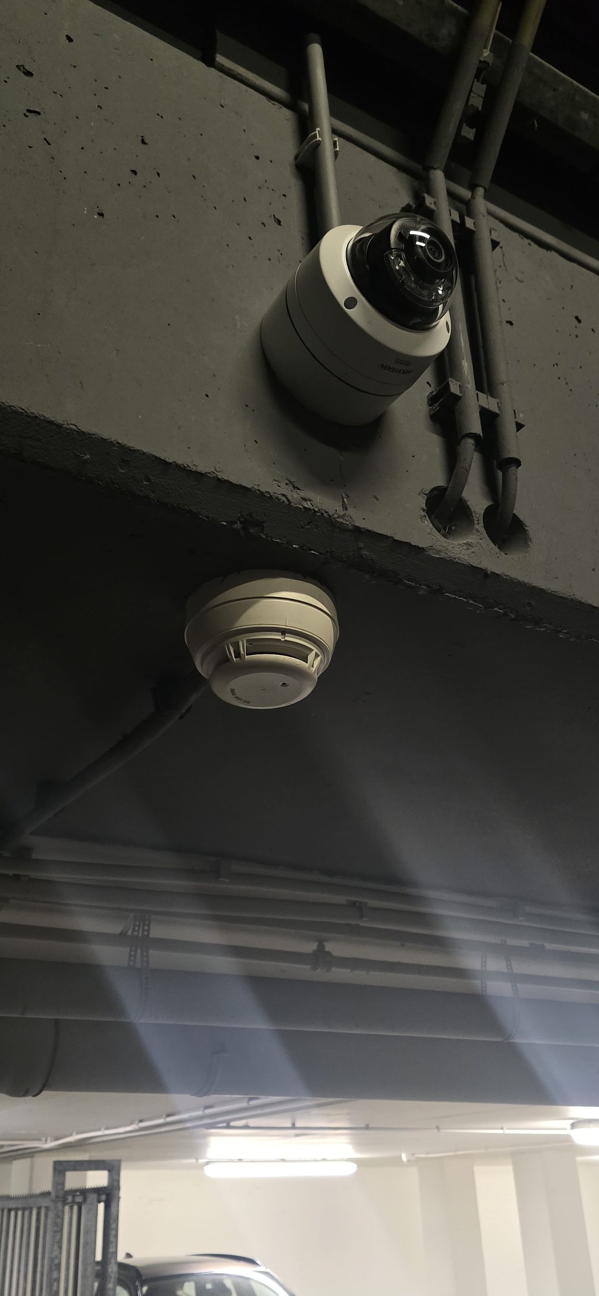 Camera en rookmelder naast elkaar aan plafond